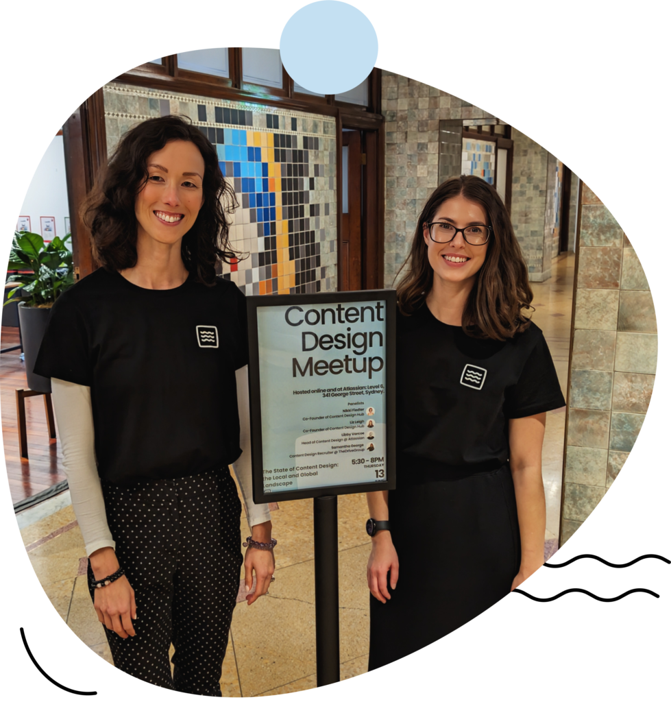 Nikki and Liz standing alongside a Content Design Hub Meetup poster at the Atlassian office